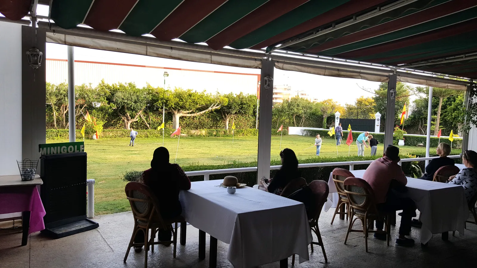 Terraza ajardinada de la finca con mesas para tomar algo